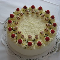 weiße Schoko-Torte mit Sahnehäubchen und Himbeeren